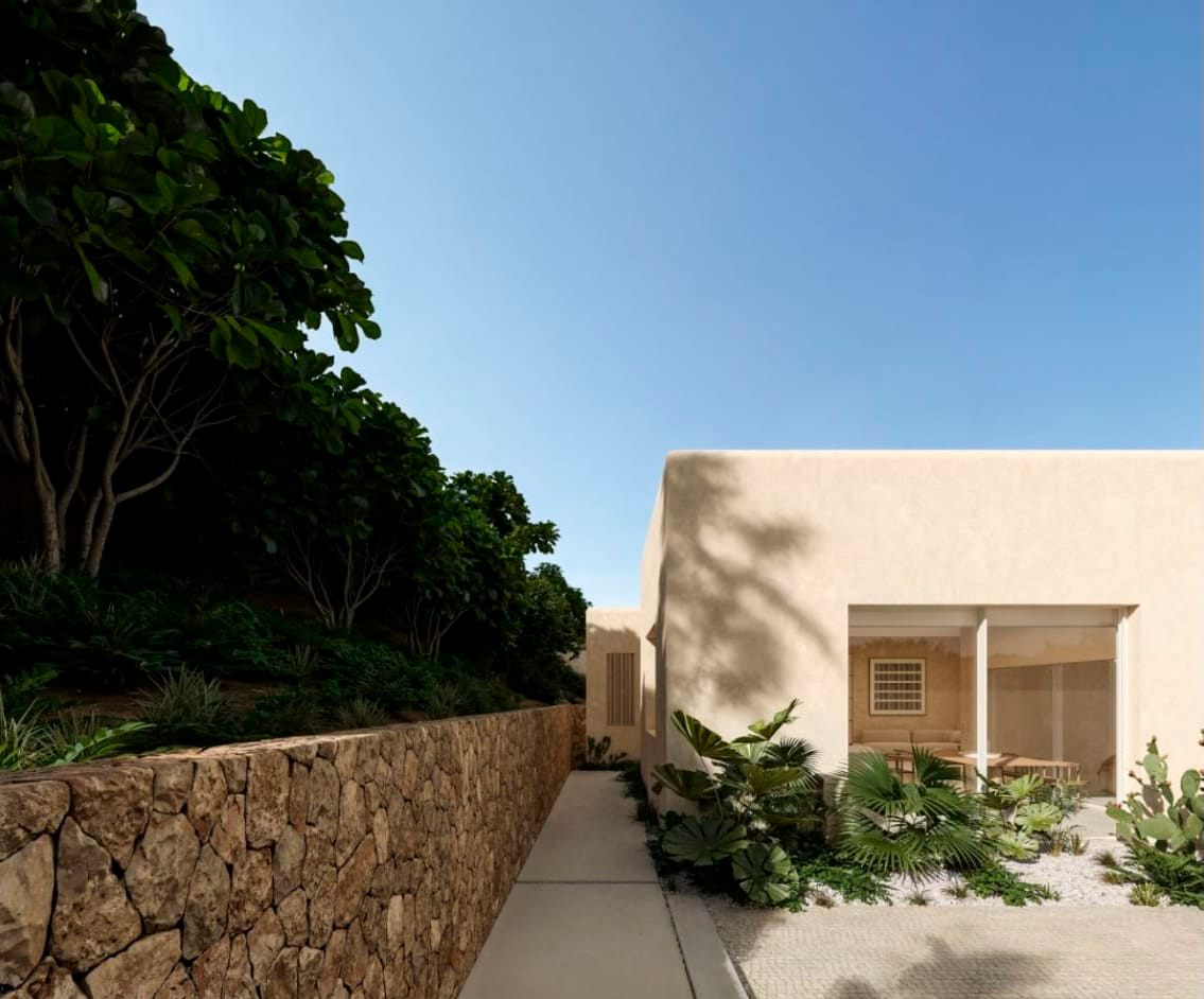 Fachada lateral de Marquesa House junto al muro de piedra y el jardín