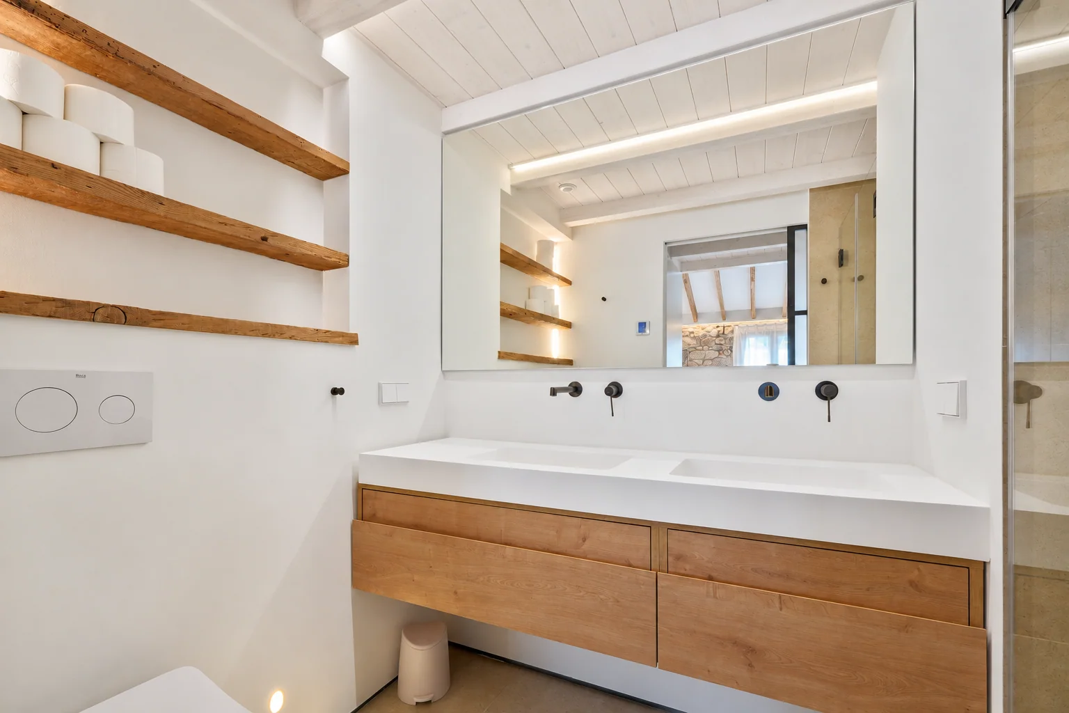 Baño con mueble de madera, espejo amplio y estantes abiertos
