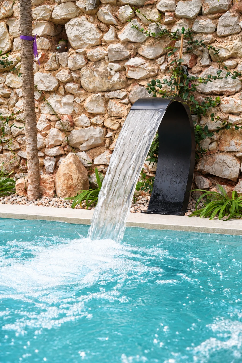 Detalle de la cascada de agua sobre la piscina