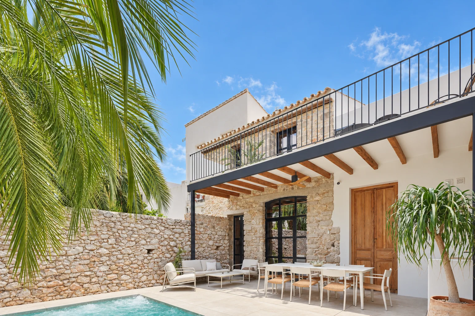 Fachada de piedra, terraza cubierta y balcón junto a la piscina