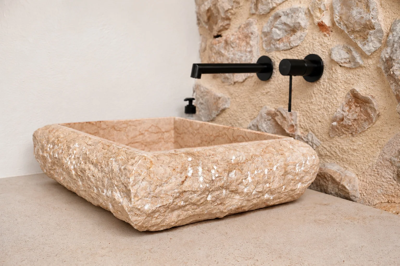 Lavabo de piedra natural y grifería negra en la zona exterior